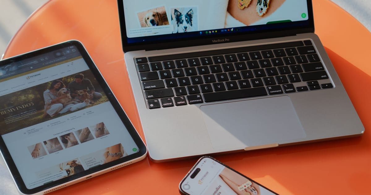 A laptop, tablet and phone showing the same website on an orange table